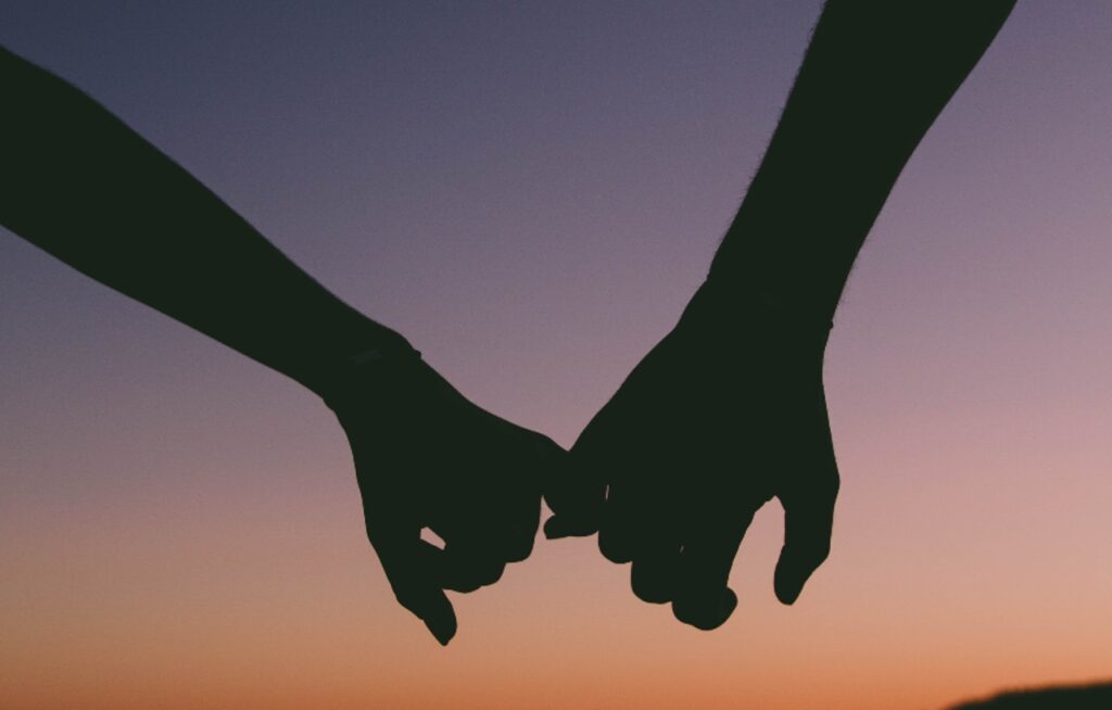 two people holding hands as the sunsets